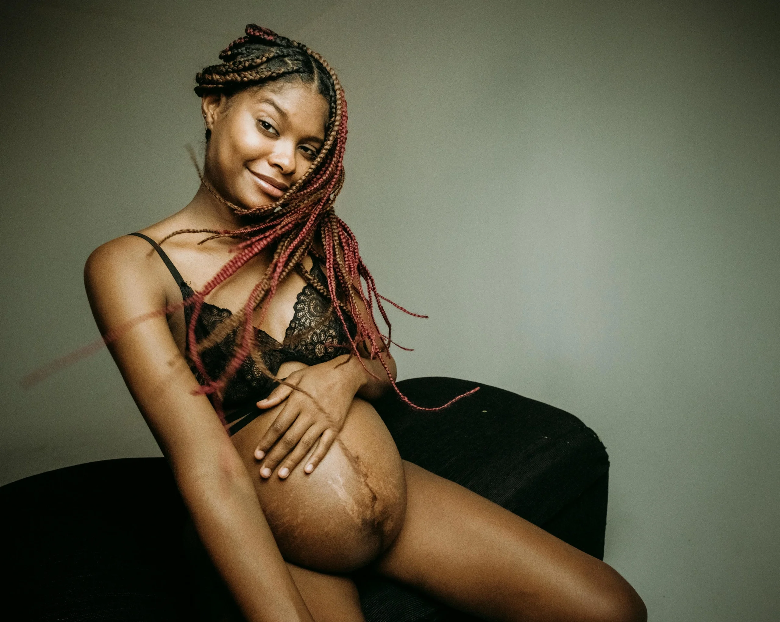 Mamá primeriza posando en un estudio, con una sonrisa radiante y su baby bump en el centro de la imagen.